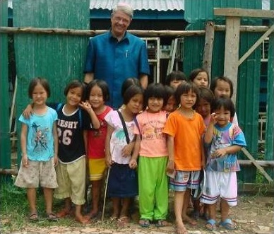 A man standing beside a group of cheerful children, with smiling faces and a heartwarming atmosphere.